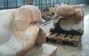 Hockender Mensch im Schneidersitz, beide Hände zum flüstern an den Mund gelegt