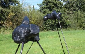 Zwei schwarze Wesen mit unbekannter Form balancieren auf drei hohen Bambusstangen