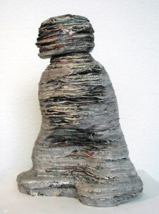 Einzelne Blätter von Illustrierten aufeinander geklebt, nach dem Trocknen in Form eines schreitenden, stilisierten Mensch geschnitzt