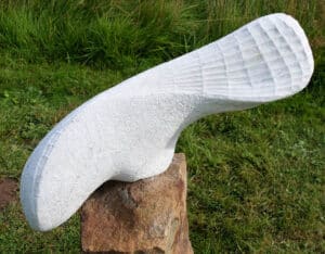 Skulptur: Fisch im Netz. Stilisierte Form, geschwungener Fischkörper, zum Teil mit Relief als Netz