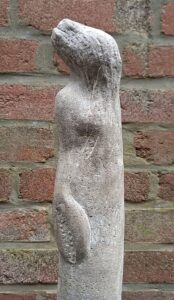 Skulptur einer stehenden, weiblichen Figur mit verschleiertem Gesicht und Krebshand/Schere