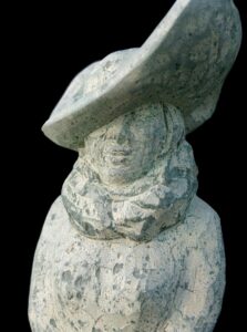 Steinskulptur einer eleganten Frauengestalt mit großem Hut